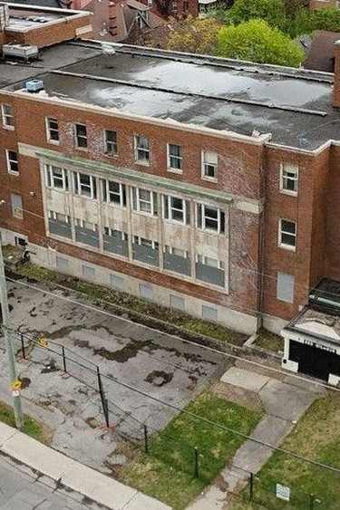 A derelict building with grass growing between cracks on the front concrete