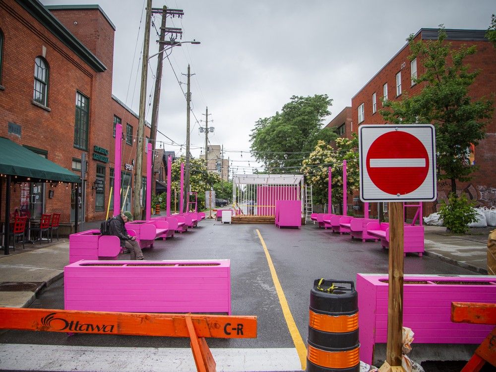  People sit and walk past temporary seating areas at the intersections of along Bank Street in Ottawa, part of the Street Seats pilot program that closes sections of the road to vehicles.