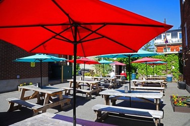 A red umbrella over a picnic table, with red and blue umbrellas visible in the background