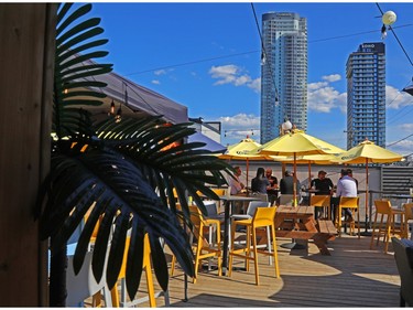 Yellow umbrellas over tables on a rooftop patio surrounded by skyscrapers