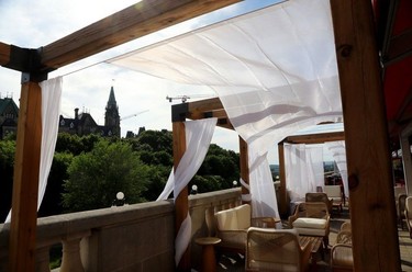 Curtains blow in the wind next to seating on a patio overlooking the Peace Tower