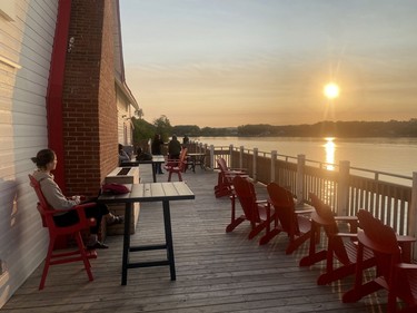 Someone sits at a table overlooking the water during sundown