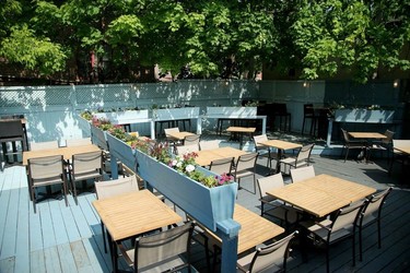 A light blue wooden deck with a row of flower boxes between tables