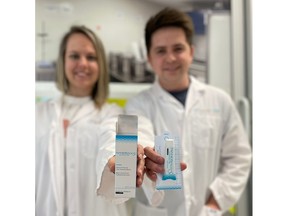 Two people in white lab coats hold up a product