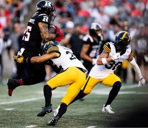 Ottawa Redblacks running back Daniel Adeboboye is tackled by Hamilton Tiger-Cats defensive back Destin Talbert
