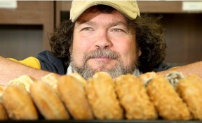 Someone poses behind a row of donuts