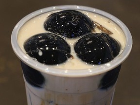 A cup of bubble tea with glossy spheres floating on top