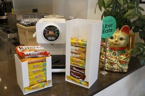 A ramen machine by stacks of ramen and a gold lucky cat