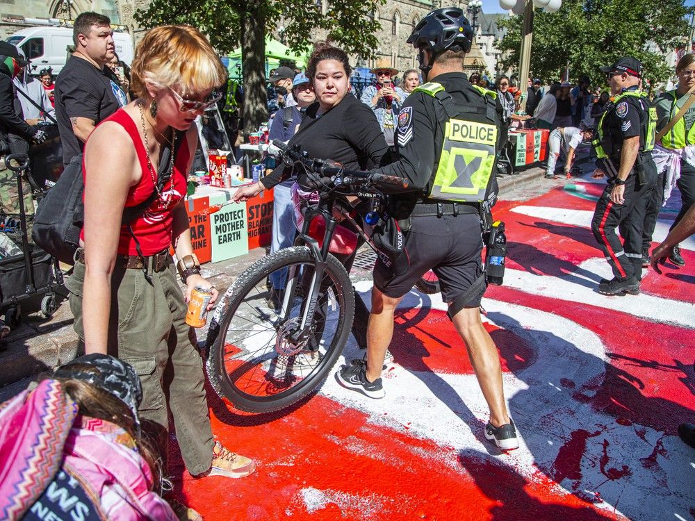  Protesters clashed with Ottawa police multiple times on Wellington Street as officers attempted to clear the roadway and stop demonstrators from painting, eventually seizing their jugs of paint after several altercations.