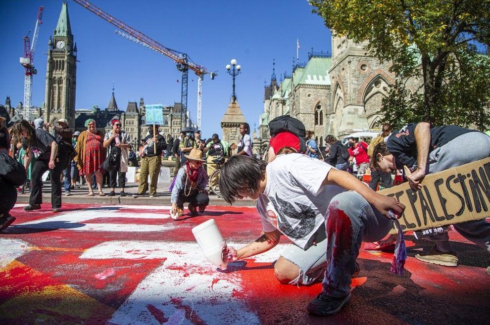  Ottawa police say two people were arrested for mischief after part of Wellington Street was painted with the words “People Peace Planet – Not Profit,” which remained closed Saturday afternoon for cleanup.