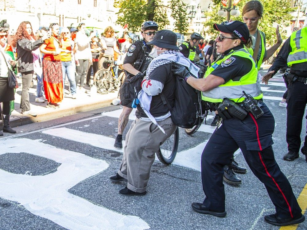  Protesters clashed with Ottawa police multiple times on Wellington Street as officers attempted to clear the roadway and stop demonstrators from painting, eventually seizing jugs of paint after several altercations.
