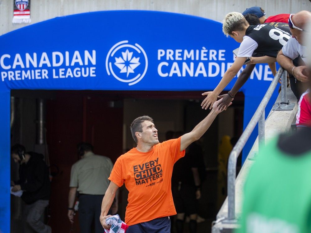  Atlético Ottawa’s Alberto Zapater greets young fans as he walks onto the field before the Saturday contest against Cavalry FC at TD Place. A number of fans and players wore orange “Every Child Matters” shirts, highlighting ongoing efforts toward reconciliation.