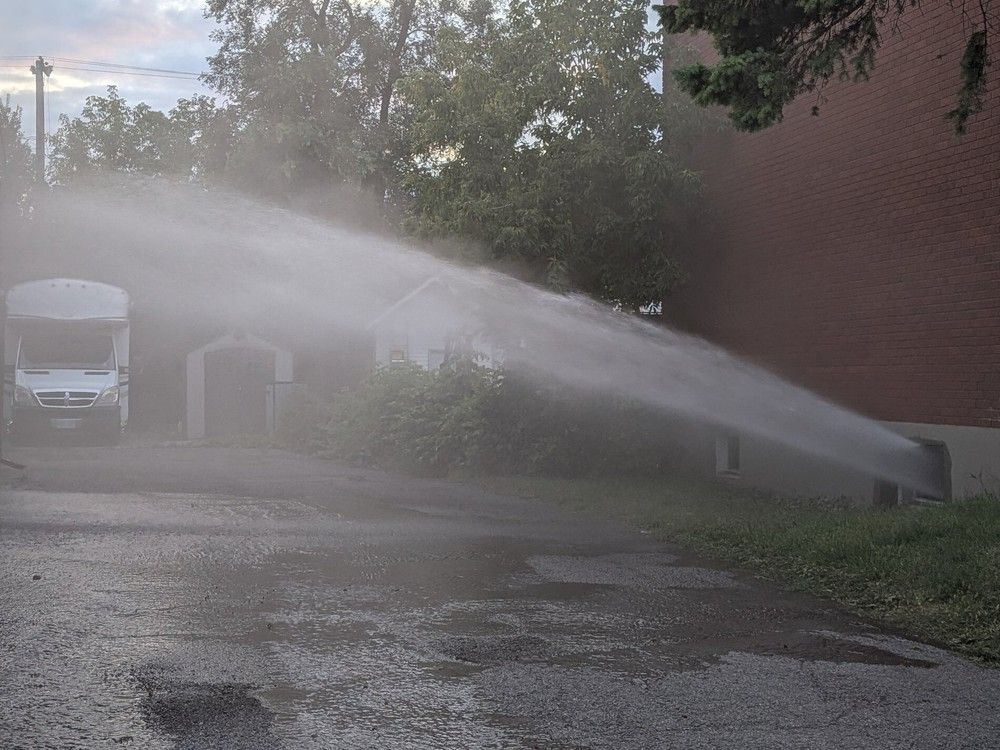  Water gushes from the basement of a building on fire on Trojan Avenue Saturday, Sept. 6.