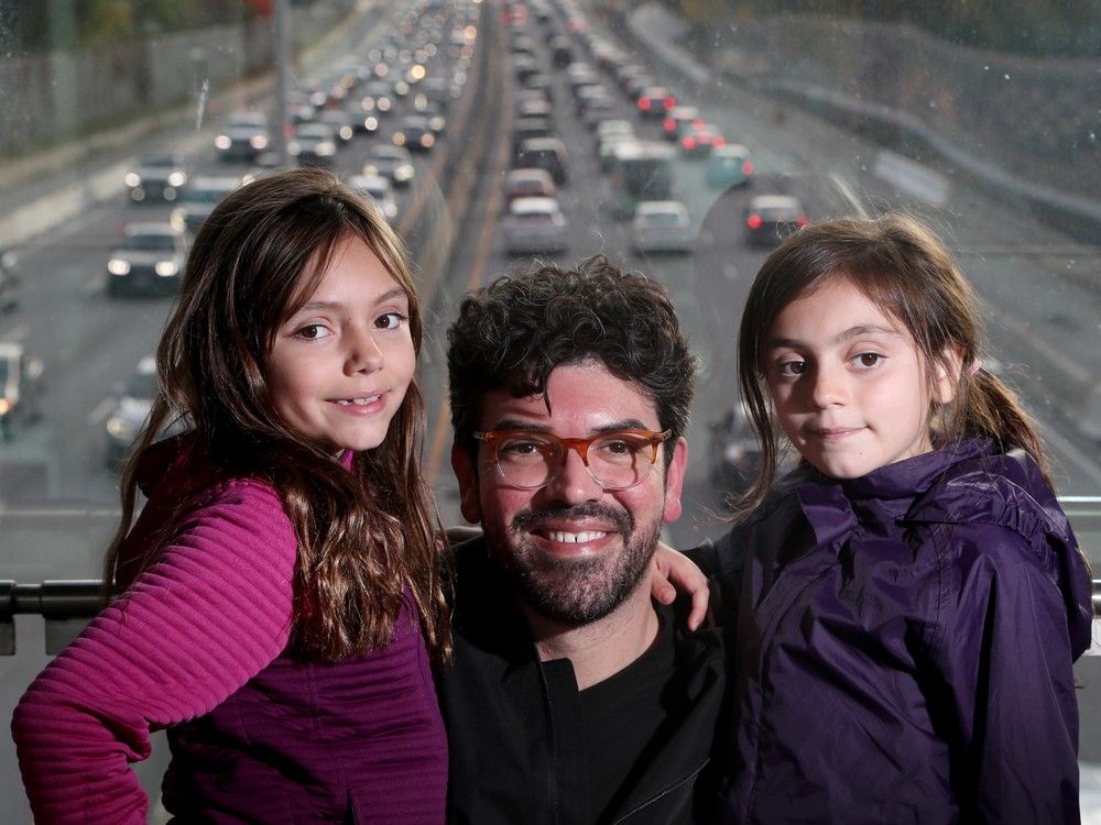 Andrew Arcello and his daughters Evelyn, 9, left, and Eleanor, 7, on the Jackie Holzman Bridge over Highway 417. In the background is Highway 417 traffic between Rochester and Carling on Friday between 4 p.m. and 5 p.m.