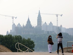 Suzannah is photographed in front of Parliament Hill by her friend Chan, both visiting from Vancouver. Suzannah was wearing a mask due to the wildfire smog that lay over Ottawa on June 6, 2025.