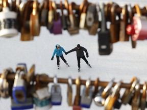 A couple holds hand while skating past the love locks at the Corktown Footbridge on the Rideu Canal in Ottawa.