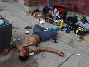 April 29, 2025 -- A man lays on Bank Street passed out from drug use in downtown Ottawa.