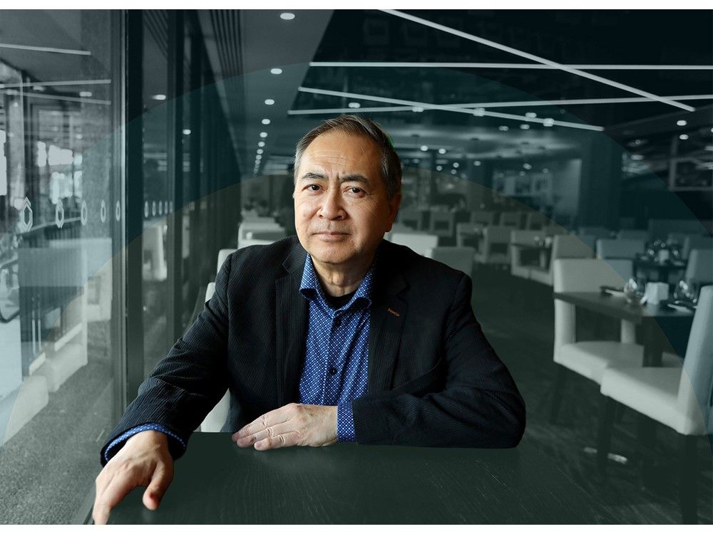 Peter Hum sits with his hand on a restaurant table