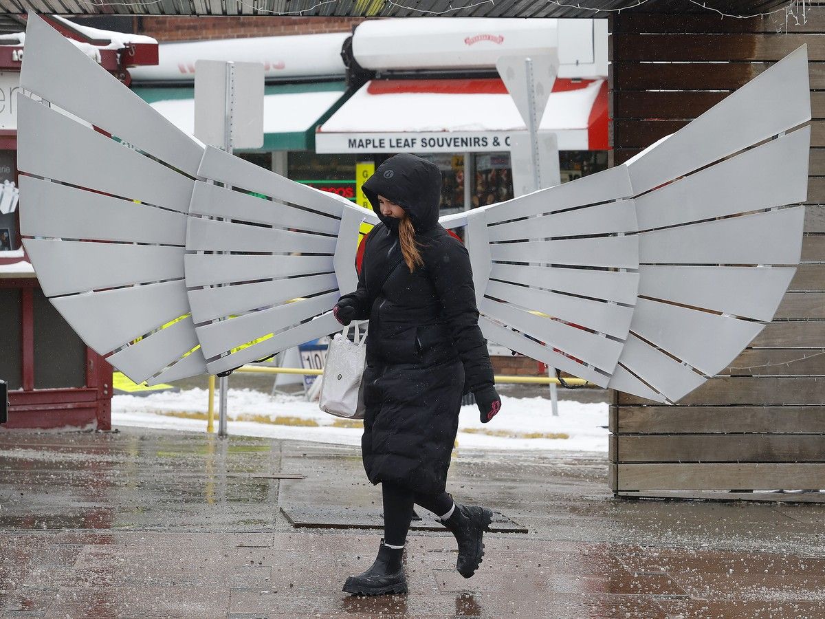  A woman looks like s snow angel as she walks in the cold past what looks like a pair of wings in the ByWard Market in Ottawa.