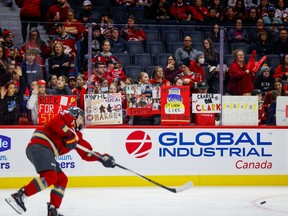 A hockey player in a red jersey takes a shot.