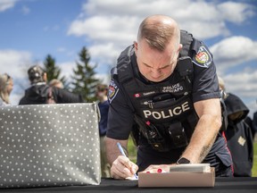 An Ottawa Police Service officer with the community police officers unit signs a note during an emotional vigil