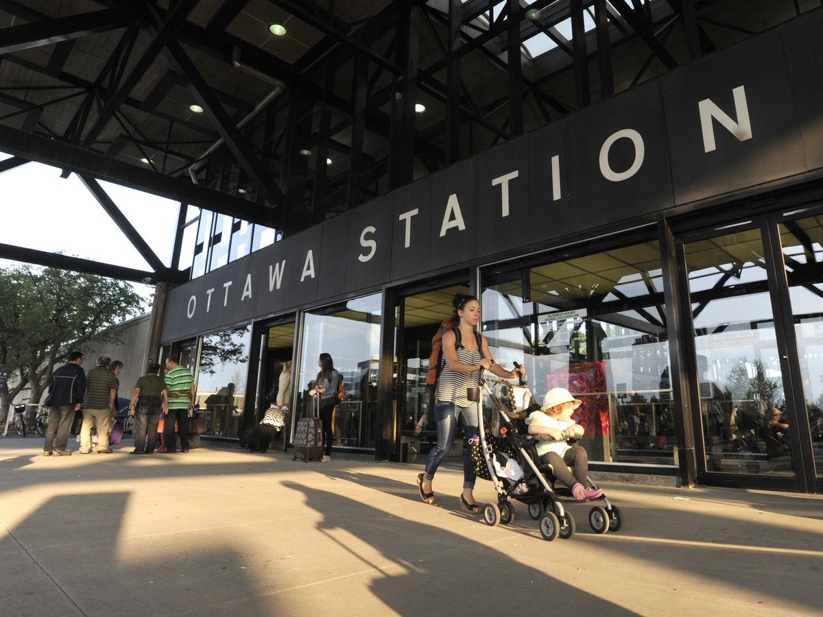 A pedestrian walks a stroller in front of the Via Rail station on Tremblay Road.