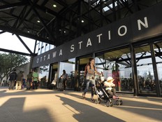 A pedestrian walks a stroller in front of the Via Rail station on Tremblay Road.
