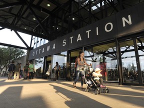 A pedestrian walks a stroller in front of the Via Rail station on Tremblay Road.