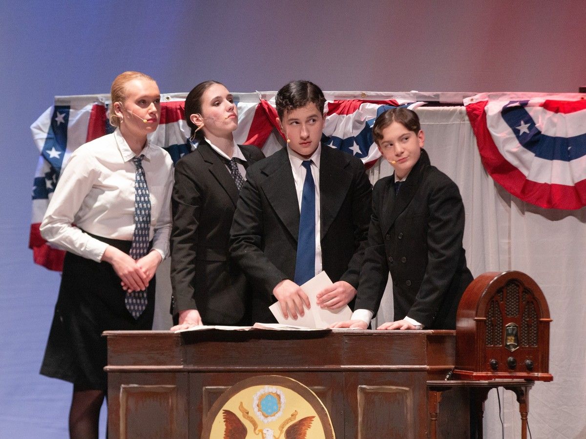 Grace MacQueen (FL), Morgan Scala (L), Michael Mortimer (R), and Jasper Siboo (FR) perform as presidential advisors, in St. Mother Teresa's production of Annie