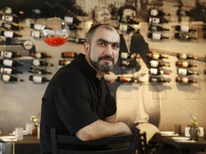 Someone in a black shirt in front of a wall of wines
