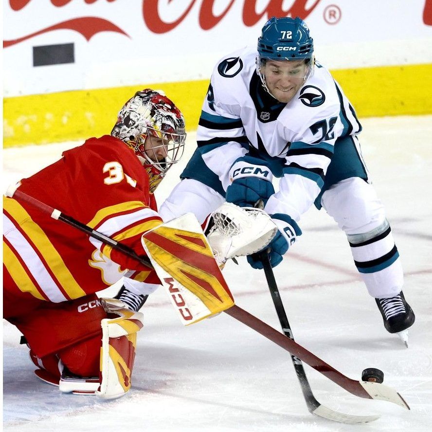 William Eklund looks to get his stick on a loose puck while in tight against Calgary Flames goalie Dustin Wolf