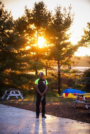 The sun sets over the Ottawa River as a security guard stands near LeBreton Stage during Ottawa Bluesfest at LeBreton Flats, Saturday, July 18, 2026.