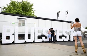 Fans take a picture in front of a Bluesfest sign during the opening night of Bluesfest at LeBreton Flats on Thursday, July 9, 2026.