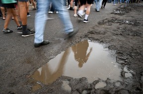 People walk by large reflective mud puddles