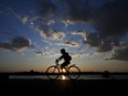 A cyclist bikes along the Ottawa River near LeBreton Flats as the sun sets.