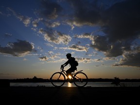 A cyclist bikes along the Ottawa River near LeBreton Flats as the sun sets.