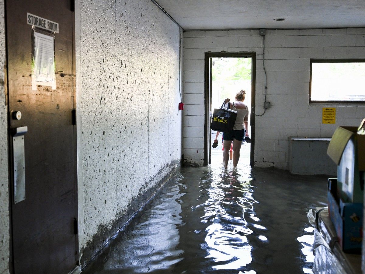 A resident of a flooded apartment building on McEwen Avenue in the Ambleside neighbourhood of Ottawa treads through water following severe flooding resulting from the torrential rainstorm that hit Ottawa on July 1, 2026. A resident of a flooded apartment building on McEwen Avenue in the Ambleside neighbourhood of Ottawa treads through water following severe flooding resulting from the torrential rainstorm that hit Ottawa on July 1, 2026.