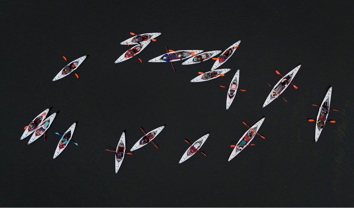 Top-down view of white kayaks on dark water.