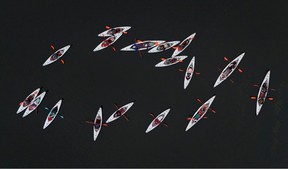 Top-down view of white kayaks on dark water.