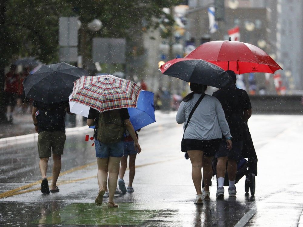 People huddle under umbrellas on Canada Day in downtown Ottawa. Photo by Jean Levac/Postmedia People huddle under umbrellas on Canada Day in downtown Ottawa. Photo by Jean Levac/Postmedia