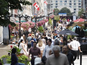 People mill around on Sparks Street outside government office buildings at lunchtime.