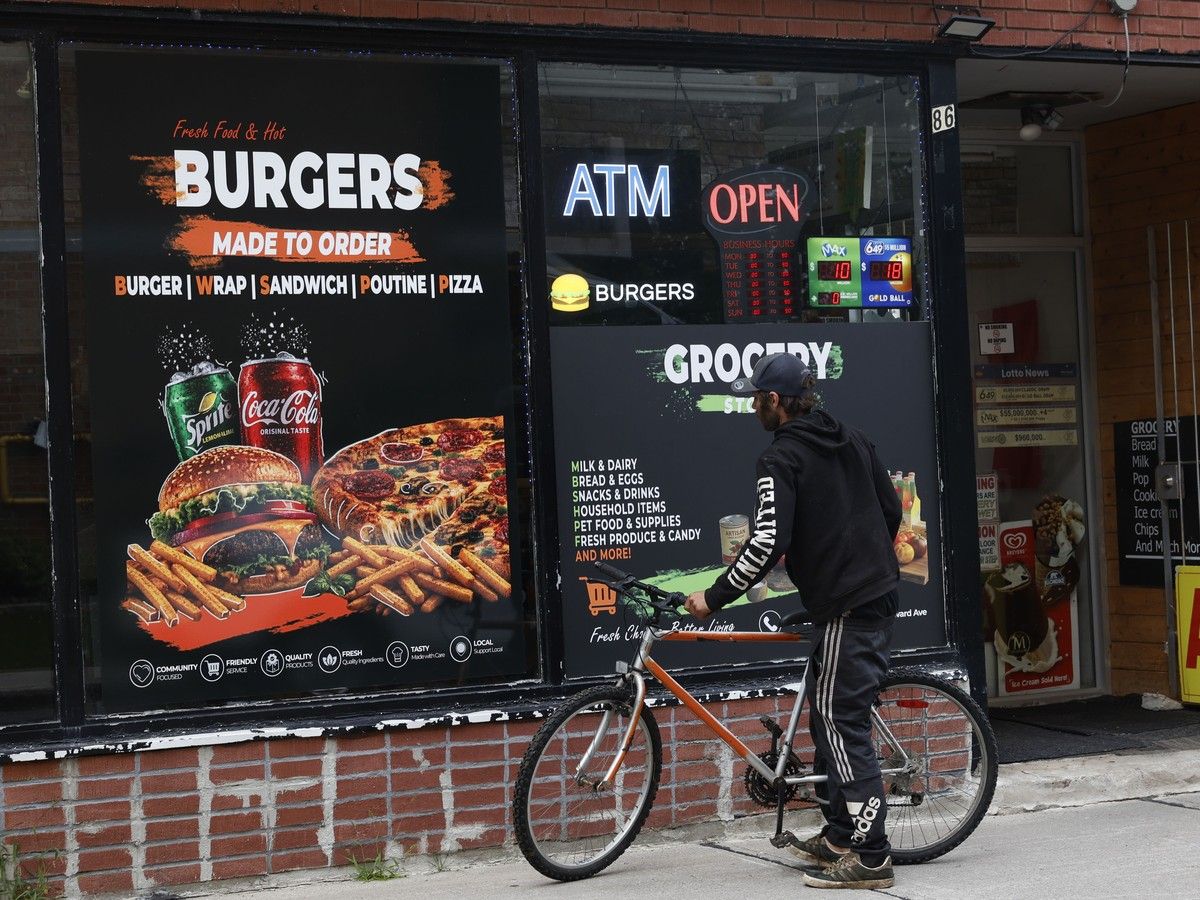 A passerby looks at an AI generated poster on the side of the Green Maple Mart & Kitchen store in Ottawa. A passerby looks at an AI generated poster on the side of the Green Maple Mart & Kitchen store in Ottawa.