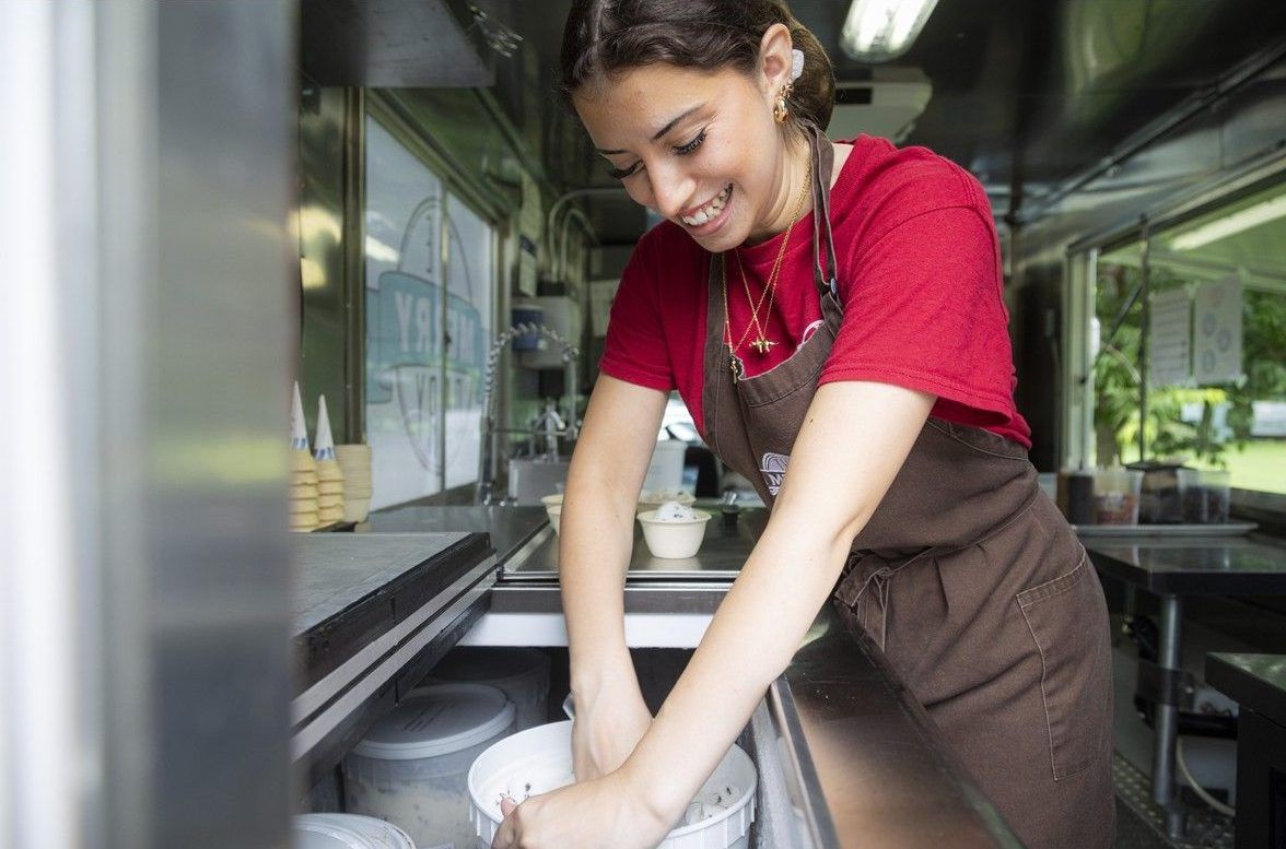 Sofia D’Ippolito, a Merry Dairy employee, digs in to keep ice cream scooped for a long line of customers at the Frank Ryan Park pop-up event on Aug. 1. Sofia D’Ippolito, a Merry Dairy employee, digs in to keep ice cream scooped for a long line of customers at the Frank Ryan Park pop-up event on Aug. 1.