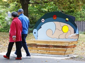 People walk by a bench designed by an Algonquin artist.