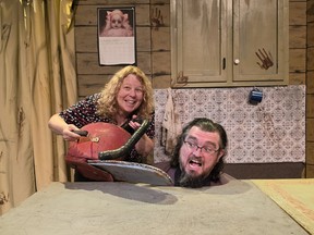 Someone holds a fake chainsaw next to the head of the director as they both make silly faces