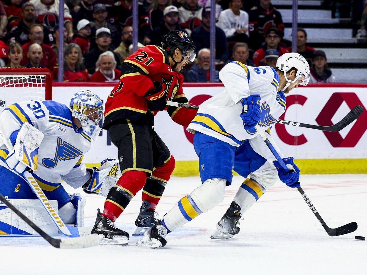 The St. Louis Blues' Philip Broberg and the Ottawa Senators' Nick Cousins vie for the puck in front of St. Louis Blues goaltender Joel Hofer during the first period at the Canadian Tire Centre on Tuesday, Oct. 13, 2026.