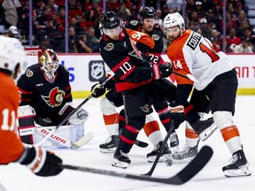The Ottawa Senators' Jordan Spence and the Philadelphia Flyers' Sean Couturier look for the puck as goalie Linus Ullmark looks on Thursday night.