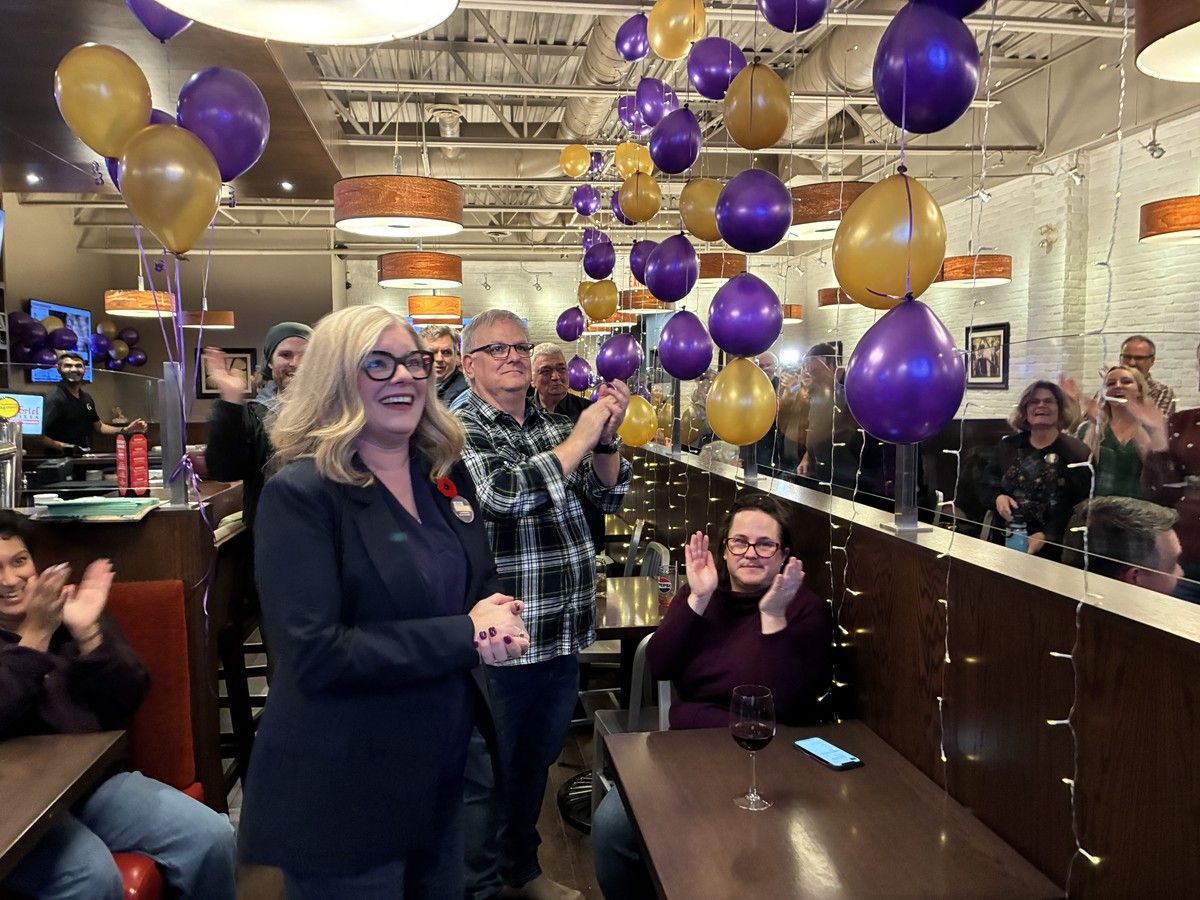 Woman surrounded by balloons smiles and cheers