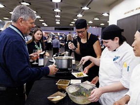 A guest waits to receive food from the Rangoon Restaurant station at the Ottawa Citizen Best Restaurants 2026 at the National Arts Centre on Monday. Chef-owner Ngun Tial is shown at right, while an Algonguin College culinary program student pitches in with food preparation.