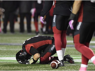 Redblacks QB Trevor Harris kneels on the field in pain after being tackled by the Tiger-Cats Ryan Mueller and Courtney Stephen (not shown) on the first-half sneak play. THE CANADIAN PRESS/Justin Tang